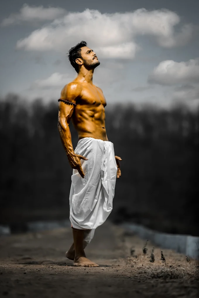 Half-naked Indian man wearing a white dhoti with a tilak, posing boldly against a dramatic background.