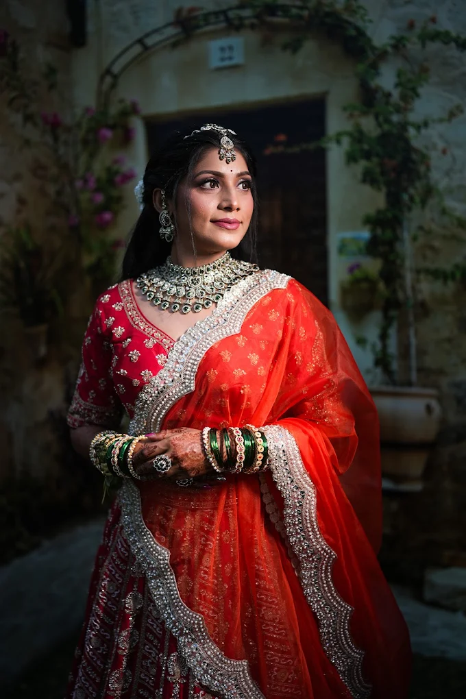 Beautiful Indian woman wearing a classic orange saree, standing in a confident pose with eternal grace.